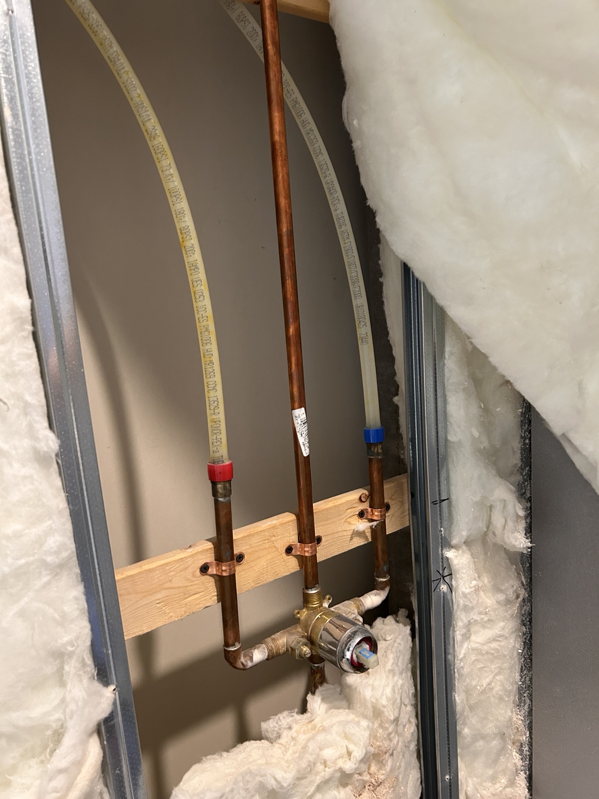 Copper and flexible water-supply lines visible in an open wall during renovation plumbing work