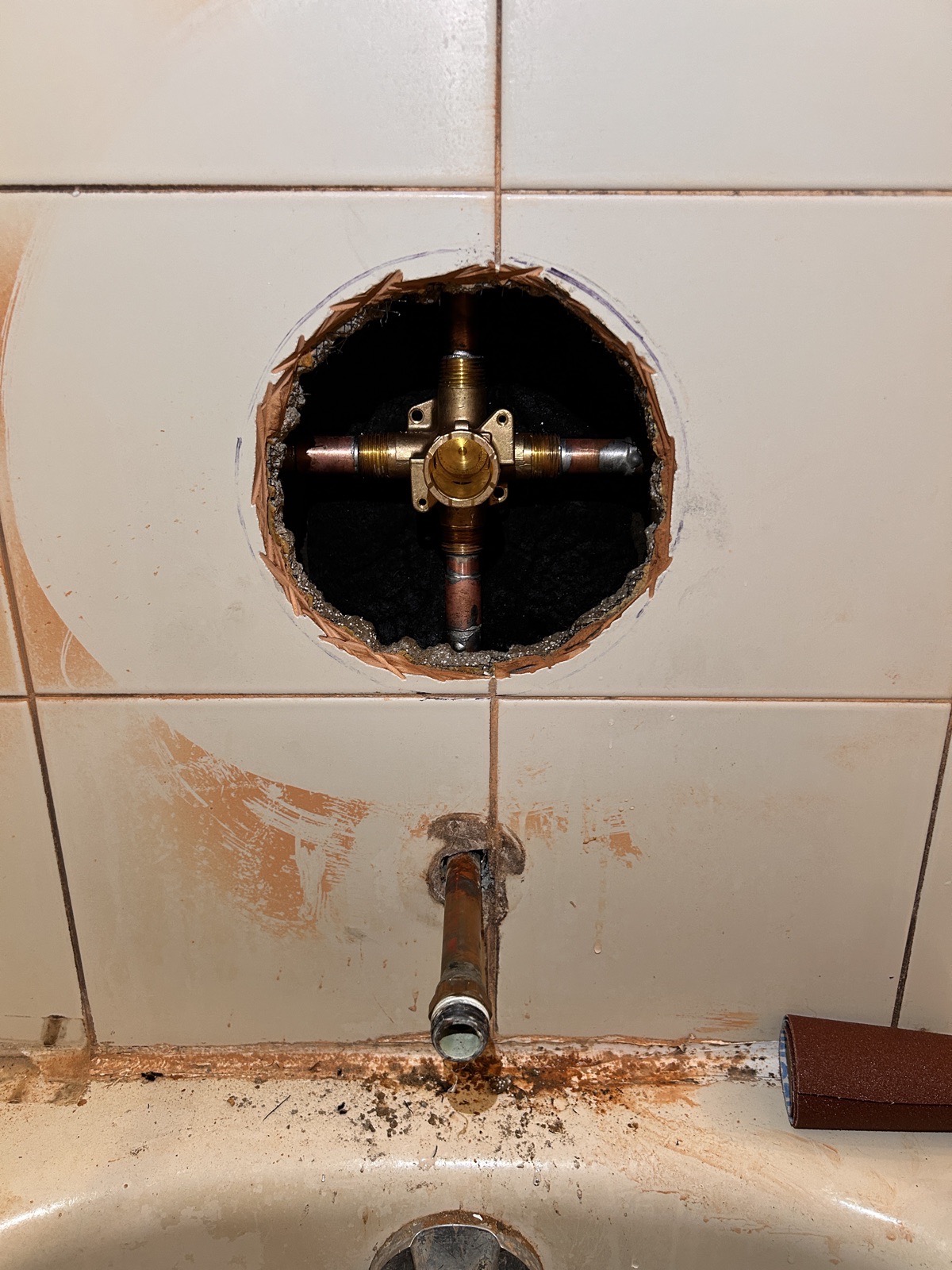 Replacement shower valve body installed through a controlled opening, displayed upright