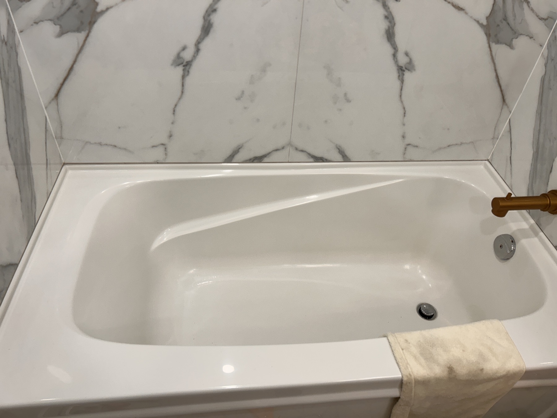 Completed bathtub and shower surround with coordinated bronze fixtures